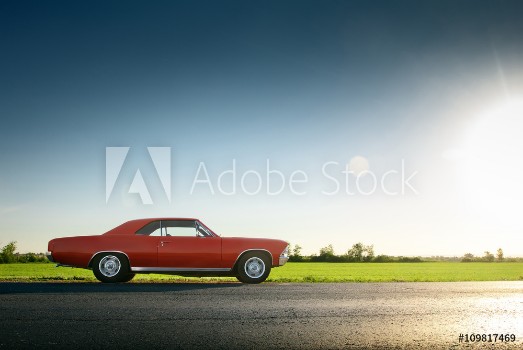Picture of Retro red car standing on asphalt road at sunset
